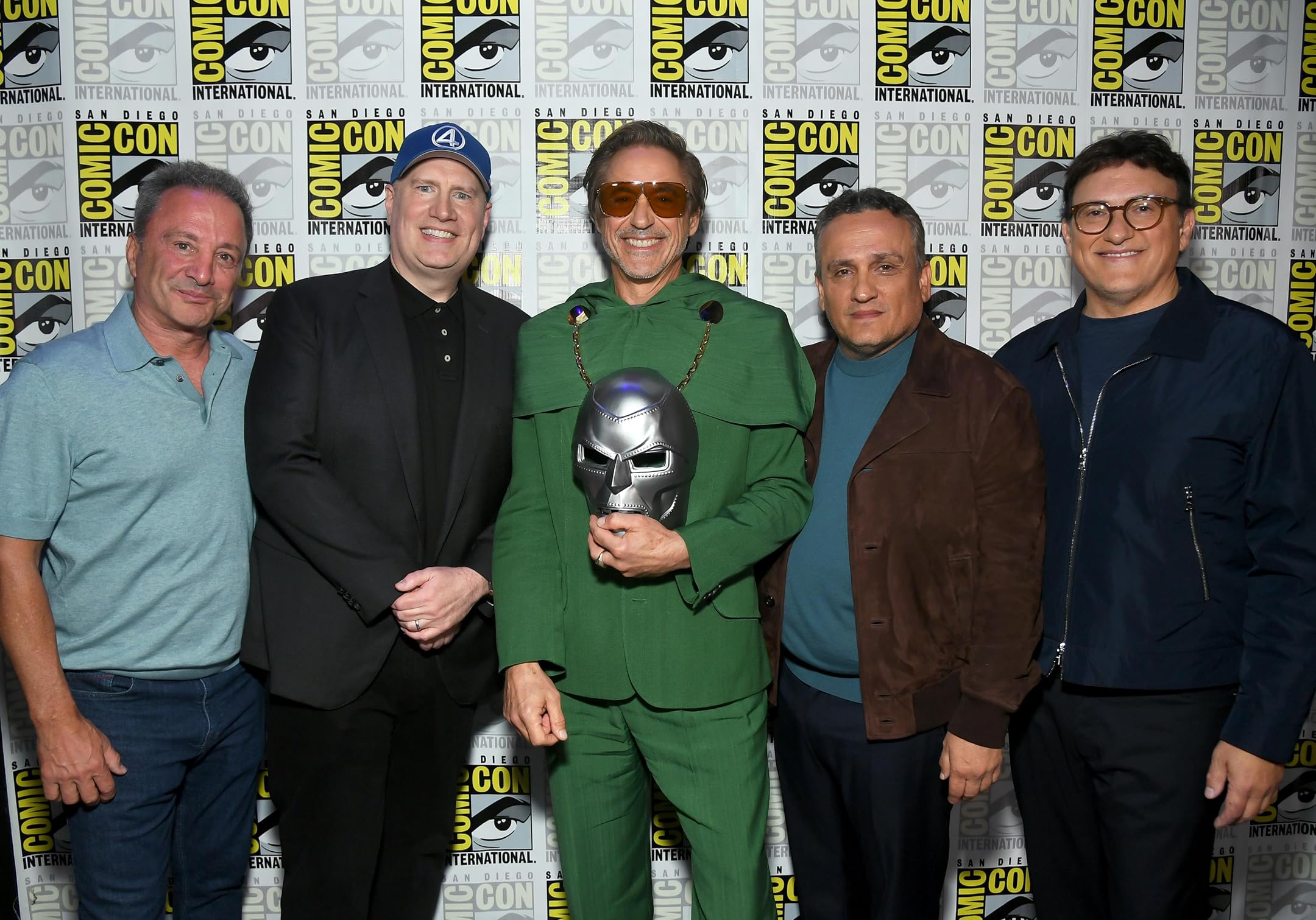 Kevin Feige with Anthony and Joe Russo on stage at San Diego Comic-Con during the Avengers: Doomsday panel, joined by Robert Downey Jr. in a Doctor Doom green suit, celebrating the big Marvel reveal.