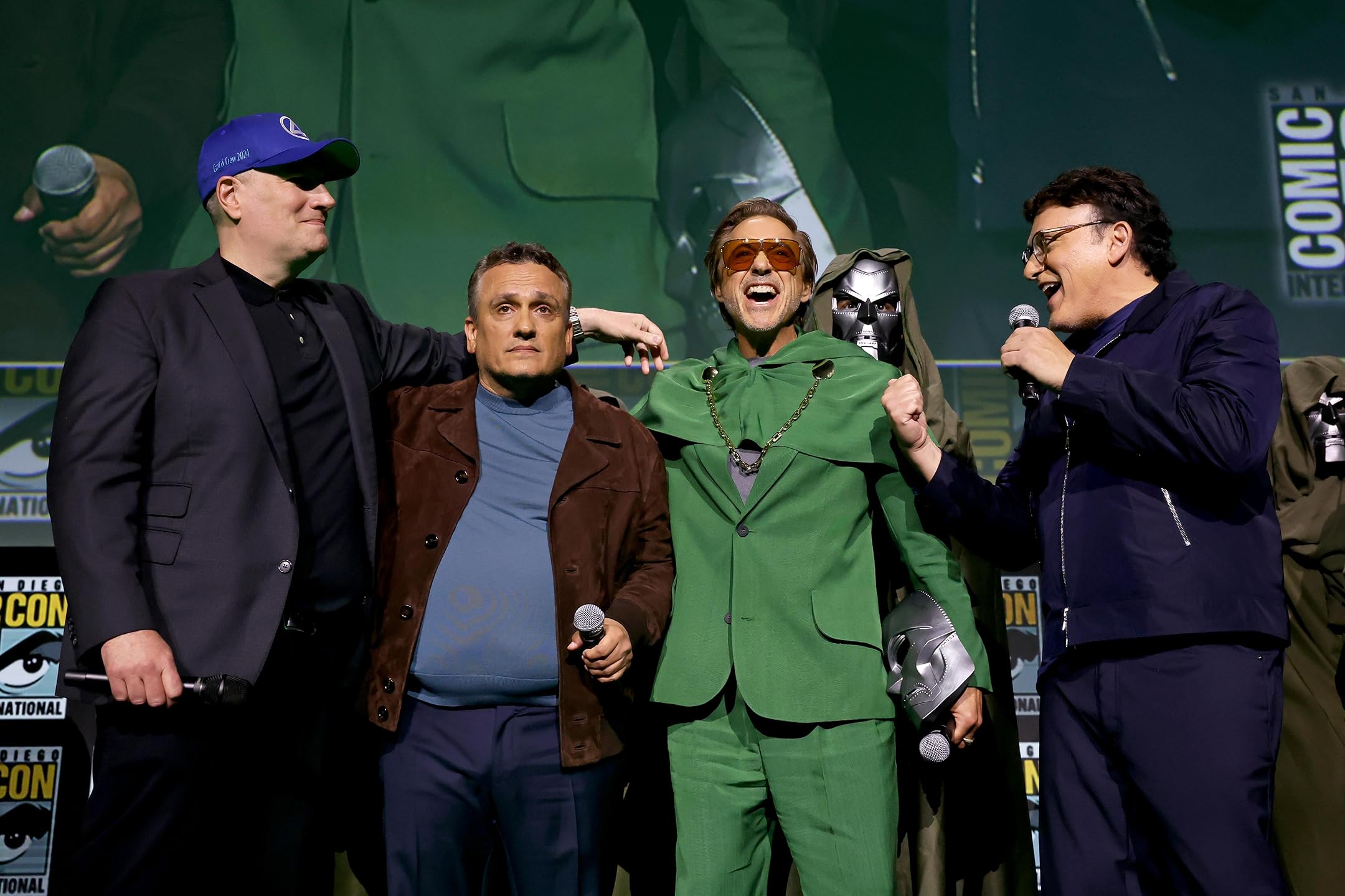 Kevin Feige with Anthony and Joe Russo on stage at San Diego Comic-Con during the Avengers: Doomsday panel, joined by Robert Downey Jr. in a Doctor Doom green suit, celebrating the big Marvel reveal.